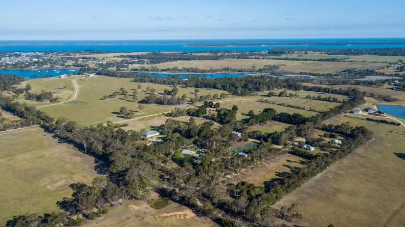 Aerial view of the ten acre Eagle Point Cottages property, farmland and the Gippsland Lakes beyond